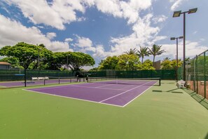 A tennis court with a net, surrounded by a green fence and trees. - Ocean views with Hawaiian-inspired decor (Lahaina)
