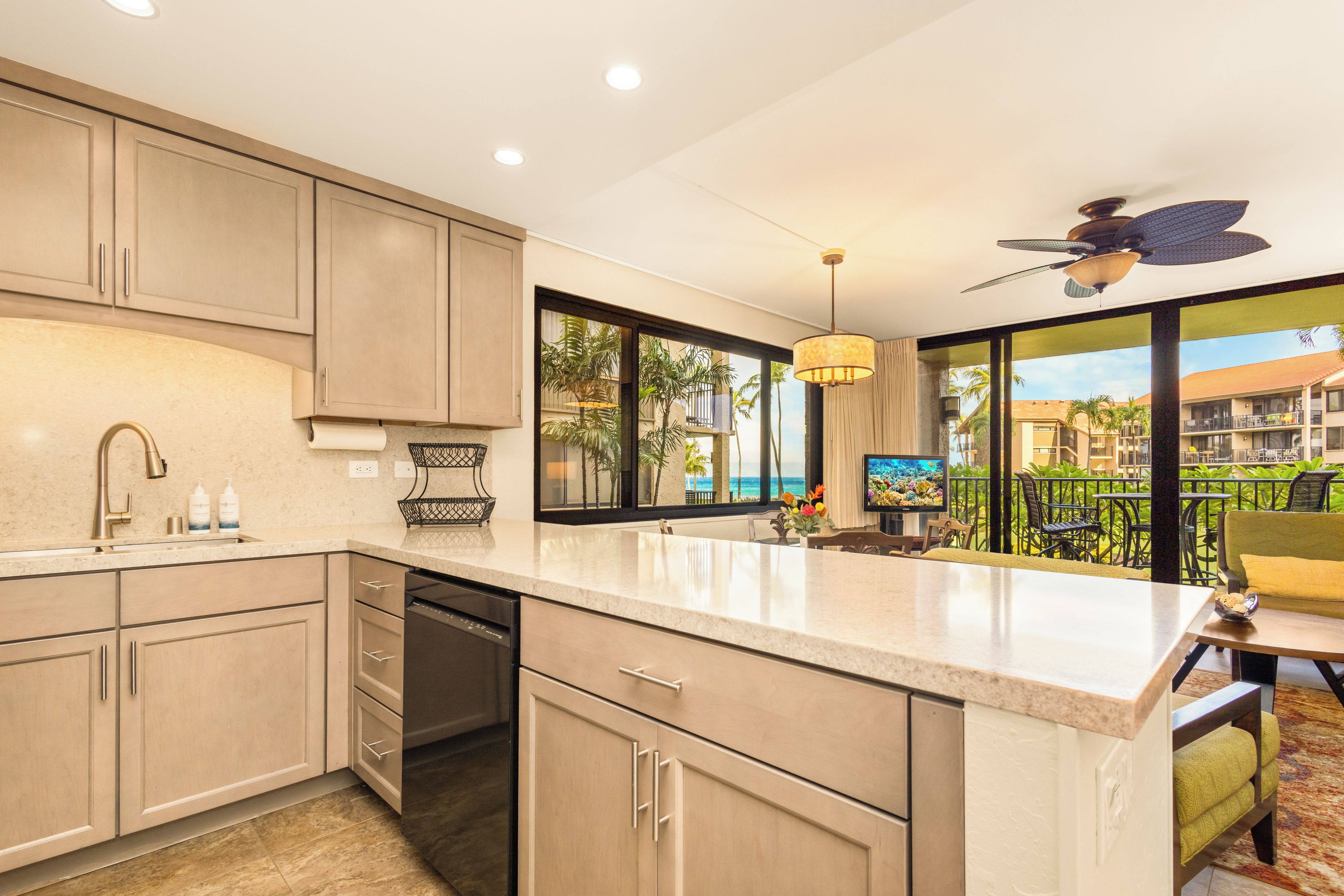 A modern kitchen with a large island, built-in appliances, and a view of the ocean.