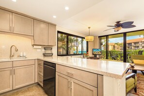 A modern kitchen with a large island, built-in appliances, and a view of the ocean. - Ocean views with Hawaiian-inspired decor (Lahaina)