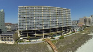 A multi-story hotel with a curved facade, located near a beach.
