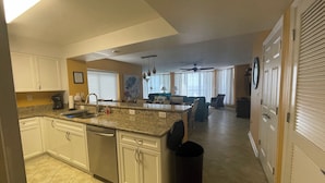 A kitchen with granite countertops, white cabinets, a dishwasher, and a ceiling fan.