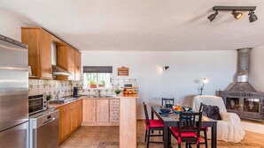 Une cuisine moderne avec des meubles en bois, un four encastré et un coin repas comprenant une table et des chaises.