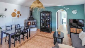 Un salon comprenant un coin repas, une cheminée, un téléviseur et une bibliothèque.