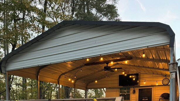 A covered outdoor seating area with wooden benches and tables, surrounded by a wooden fence and potted plants. - Country Escape Home in the Woods- Chesapeake, VA (Chesapeake)