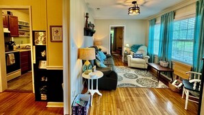 A spacious living room with a wooden floor, a sofa, a coffee table, and a dining area with a table and chairs. - Country Escape Home in the Woods- Chesapeake, VA (Chesapeake)