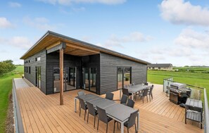 Et moderne hus med en terrasse, udendørs møbler og grill.
