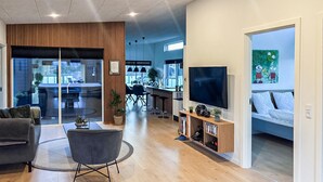 A modern living room with a sofa, a TV, and a dining area visible through glass doors. - Lovely home in Spøttrup with WiFi (Spøttrup)