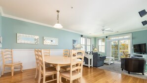 Een ruime woonkamer met een eethoek, een bank, een televisie en een balkon met uitzicht.