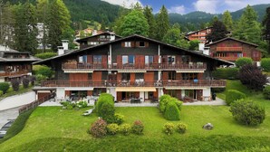 Een hotel in chaletstijl met een tweelaags gebouw, balkons en een verzorgde tuin.