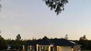 A residential house with a gravel driveway, a garage, and a well-lit entrance.