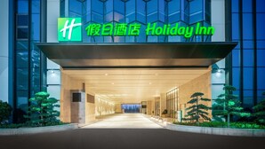 A Holiday Inn hotel entrance with a modern glass facade and a green sign. - Holiday Inn Zhengzhou High Tech Zone by IHG (Zhengzhou)