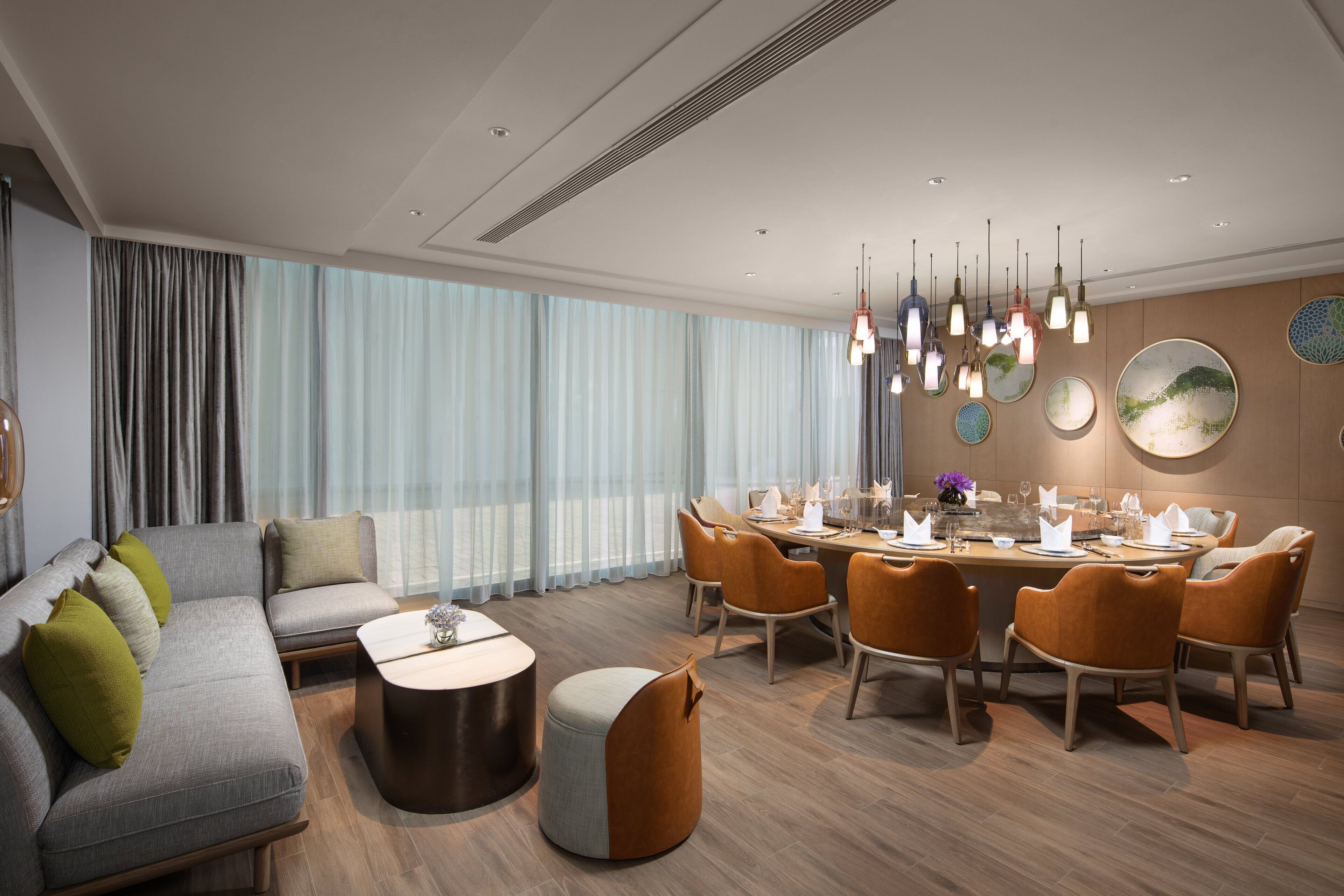 A modern living room with a sofa, ottoman, and dining area with chairs and a table.