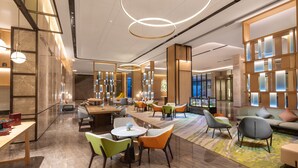 A modern hotel lobby with a variety of seating options, including round tables and chairs, and a large sofa area. - Holiday Inn Zhengzhou High Tech Zone by IHG (Zhengzhou)