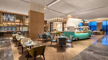 A modern restaurant with a central food truck, multiple seating areas, and a variety of food displays.