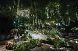 A lush indoor garden with hanging plants, a mist feature, and white chairs arranged for seating. - Holiday Inn Zhengzhou High Tech Zone by IHG (Zhengzhou)
