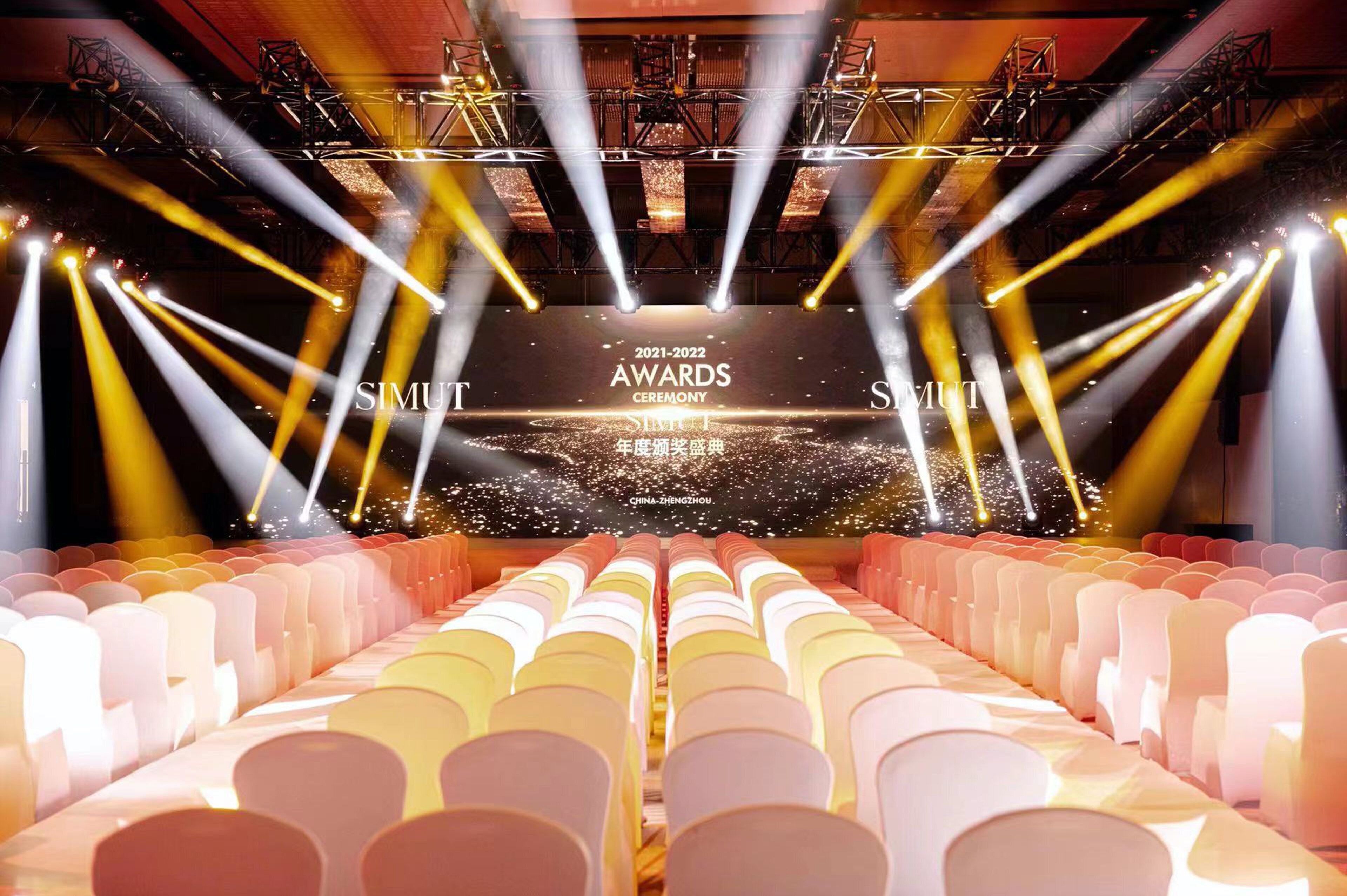 A stage with a large screen displaying '2021-2022 AWARDS CEREMONY' text, surrounded by rows of chairs.