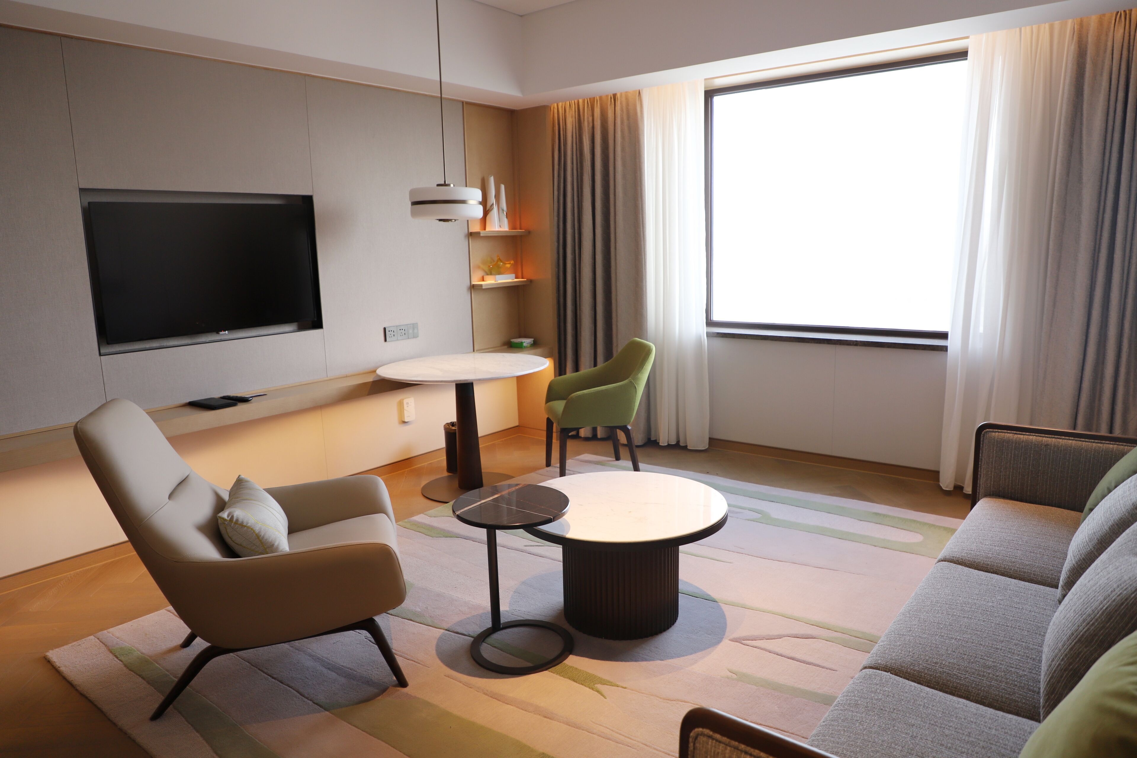 Ein modernes Wohnzimmer mit einem Flachbildfernseher, einem runden Couchtisch und zwei Sofas.