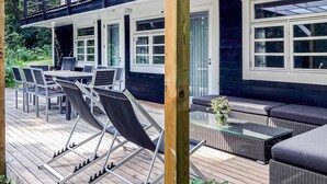 An outdoor deck with a dining area, seating, and a glass table.