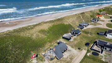 Oversigtsbillede af en kystejendom med flere huse, et flag og en strand.