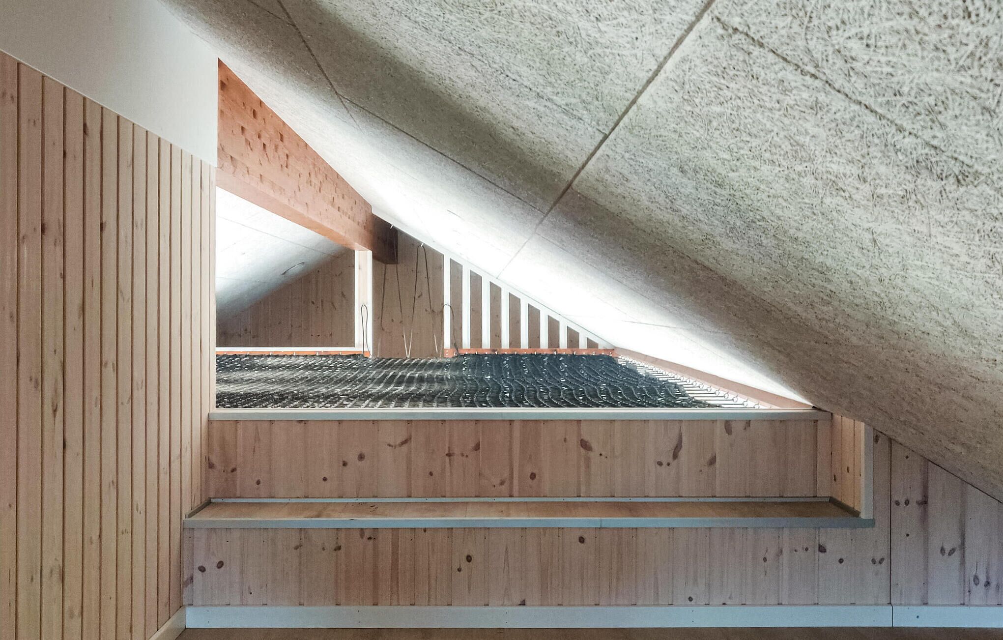 An attic space with wooden beams, a sloped ceiling, and a view of the roof.