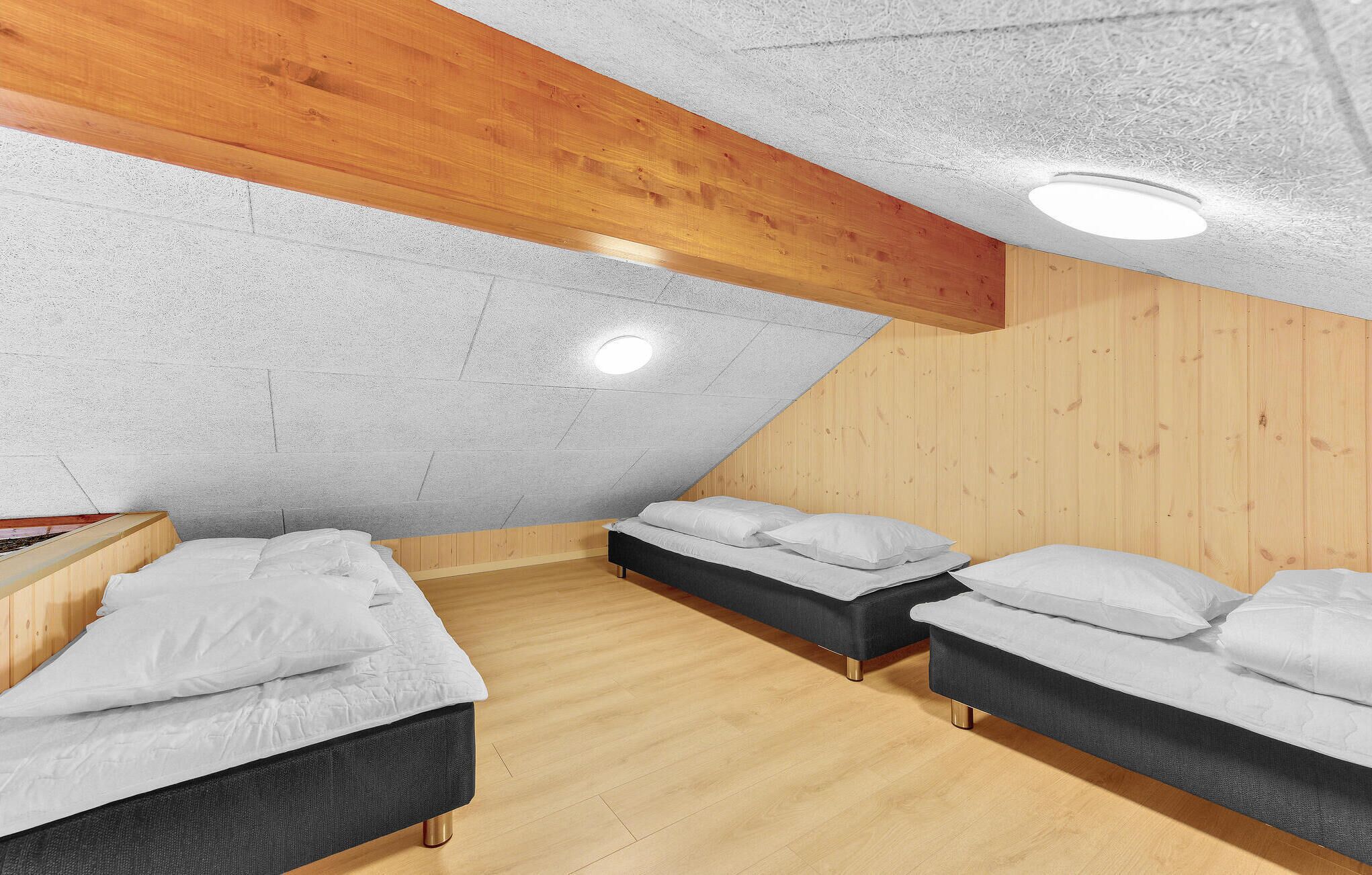 A bedroom with two beds, wooden beams, and a sloped ceiling.