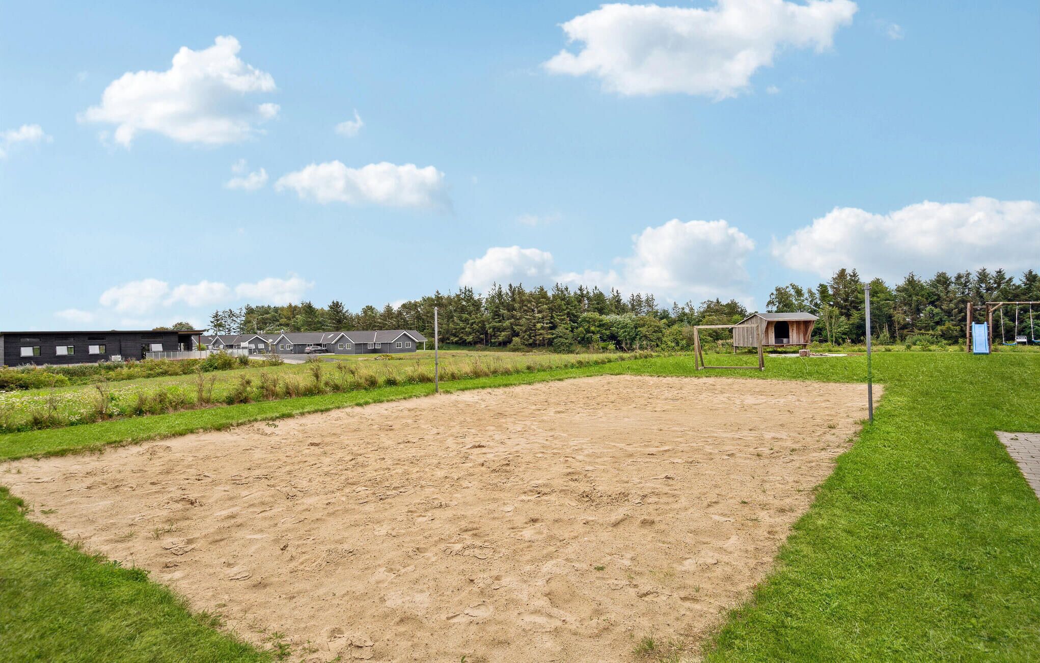 Een sportveld met een aarden baan, omringd door gras en bomen.