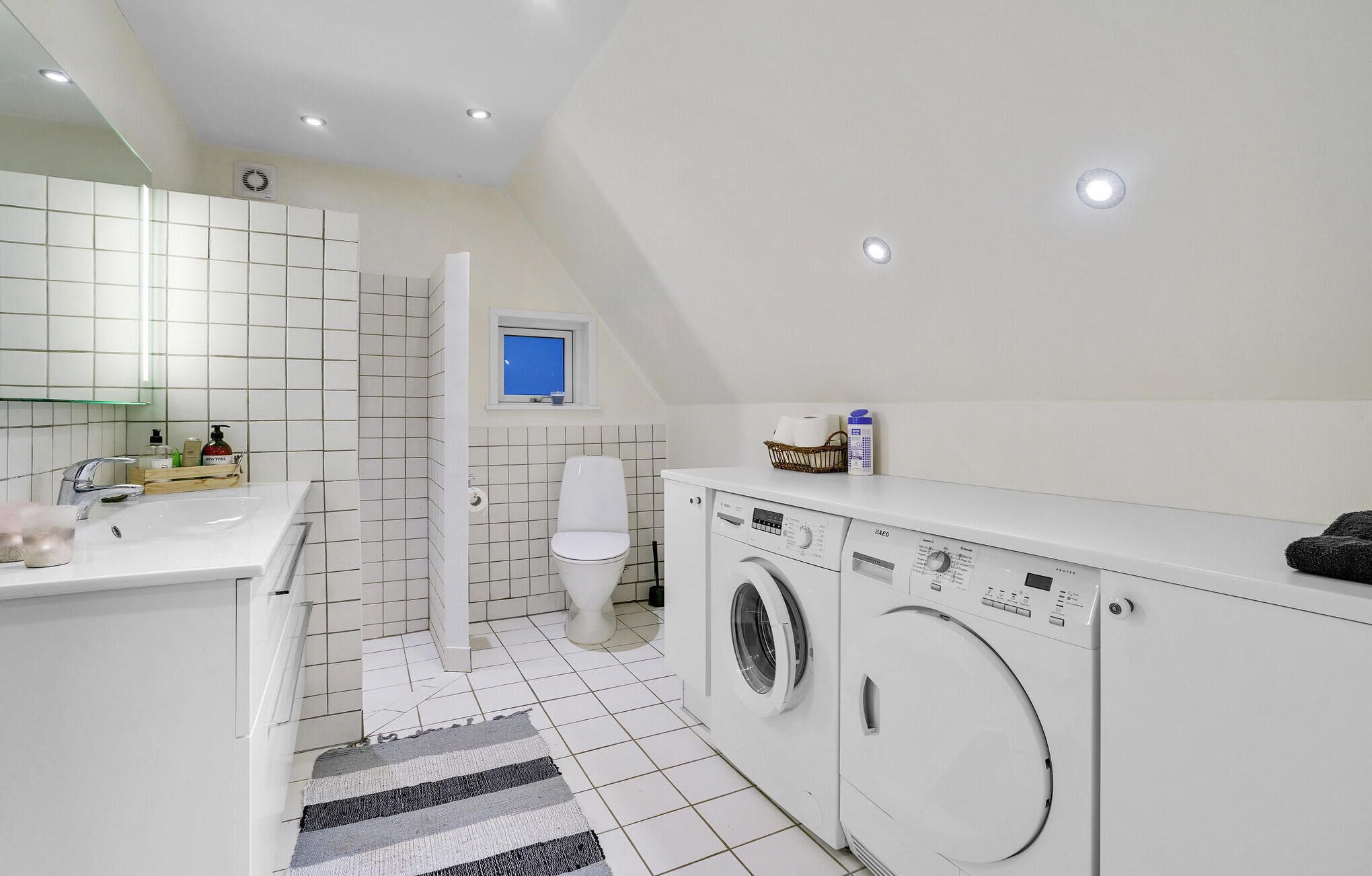 A compact, modern bathroom with a sink, toilet, and a washing machine.