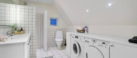 A compact, modern bathroom with a sink, toilet, and a washing machine.