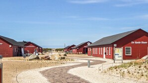Une rangée de bâtiments en bois peints en rouge, avec un ciel dégagé.