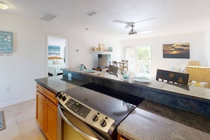 A modern kitchen with a large island, built-in oven, and a dining area with a view of the ocean. - Walk to The Best Restaurants, Beaches, and Activities. Heated Pool. Fabulous Location. (St. Pete Beach)