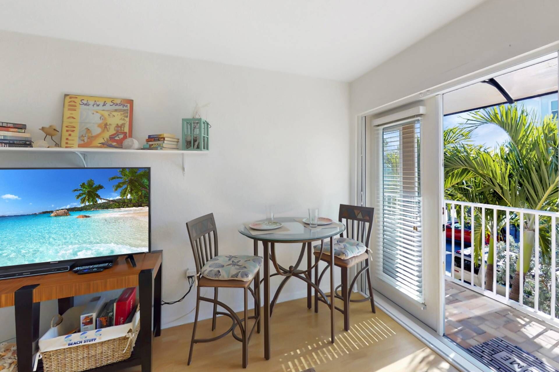 Un balcon équipé d’une télévision, de chaises et d’une table.