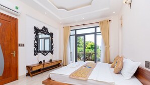 Un dormitorio con una cama grande, un banco de madera, un espejo decorativo y vistas a zonas verdes.