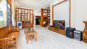 Amplia sala de estar con muebles de madera, un televisor y una escalera que sube a un piso superior.