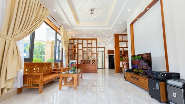 Un salón amplio con un conjunto de sofá de madera, una mesa de comedor y un televisor.