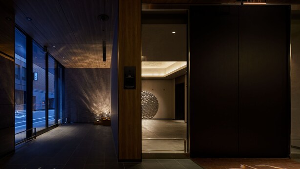 A modern interior with a wooden ceiling, a large spherical light fixture, and a dark-toned door. - the b ginza (Tokyo)