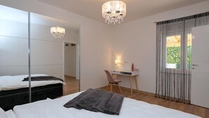 Ein Schlafzimmer mit einem Bett, einem Schreibtisch, einem Stuhl, einem Spiegel und einer Kristallleuchter.