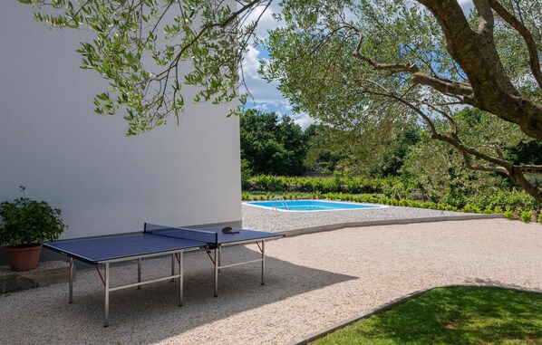 An outdoor ping pong table set up on a gravel surface with a pool in the background. - Stunning home in Zmijavci (Zmijavci)