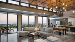 A spacious living area with a large sofa, a coffee table, and a view of the city. - Executive 9 bedroom villa with a heated pool (Daratsos)