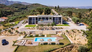 A modern villa with a swimming pool, outdoor seating, and a view of the surrounding hills. - Executive 9 bedroom villa with a heated pool (Daratsos)