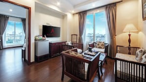 Ein modernes Hotelzimmer mit Essbereich, Fernseher und Blick auf die Stadt.