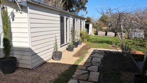 Una casa con un sendero de piedra que lleva a una puerta, rodeada de plantas en macetas y un césped bien cuidado.