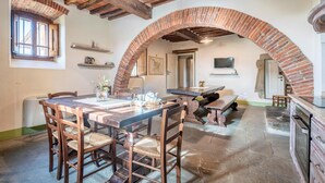 Un comedor con arco de ladrillo, muebles de madera y piso de piedra.