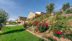 Un edificio de piedra con jardín y piscina.
