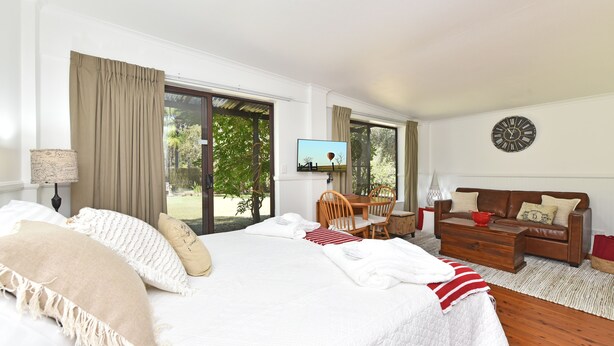 A hotel room with a bed, a sofa, a TV, and a view of the outdoors. - Olive Grove 1 - Your Perfect Hunter Valley Wedding Stay & Wine Country Escape (Pokolbin)