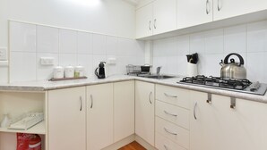 A modern kitchen with white cabinets, a gas stove, a kettle, and a coffee maker. - Olive Grove 1 - Your Perfect Hunter Valley Wedding Stay & Wine Country Escape (Pokolbin)