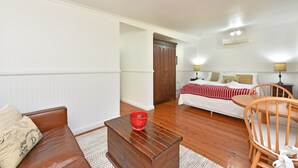 A bedroom with a bed, bedside lamps, a wooden nightstand, a wooden chair, and a red colander on a wooden table. - Olive Grove 1 - Your Perfect Hunter Valley Wedding Stay & Wine Country Escape (Pokolbin)