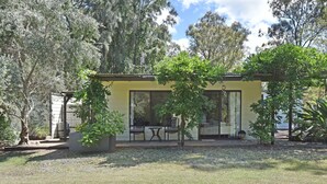A yellow building with a patio area, two chairs, and a table. - Olive Grove 1 - Your Perfect Hunter Valley Wedding Stay & Wine Country Escape (Pokolbin)