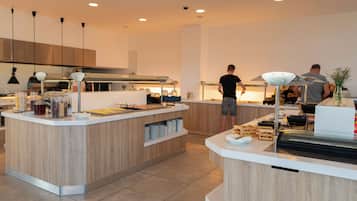 Une cuisine moderne avec un îlot central, un éclairage suspendu et une personne qui prépare des aliments.