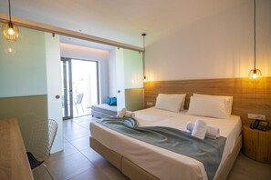A hotel room with a large bed, a desk, and a chair. There is a wooden headboard and a small side table with a phone.