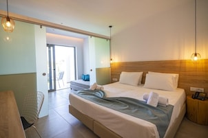 Habitación de hotel con una cama grande, un escritorio y una silla. Cuenta con un cabecero de madera y una mesita de noche con un teléfono.